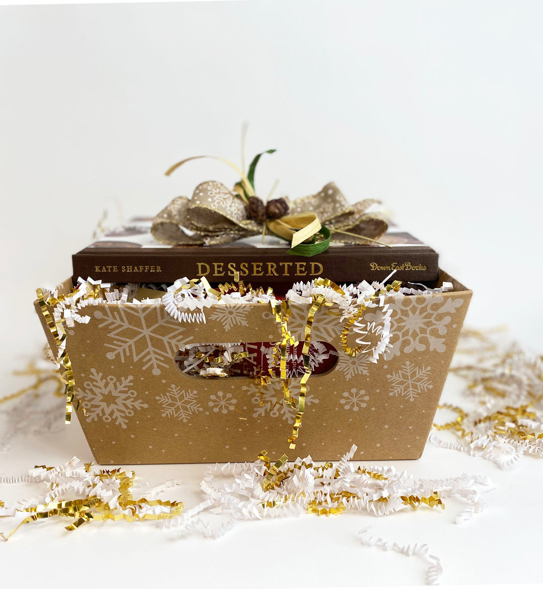 A decorative gift box with a bow surrounded by festive tinsel and Ragged Coast Chocolates Baking Chocolate.