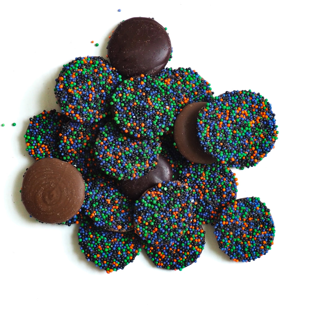 A pile of round Halloween Chocolate Party Bundle chocolates, some plain and some topped with orange, green, and purple sprinkles.