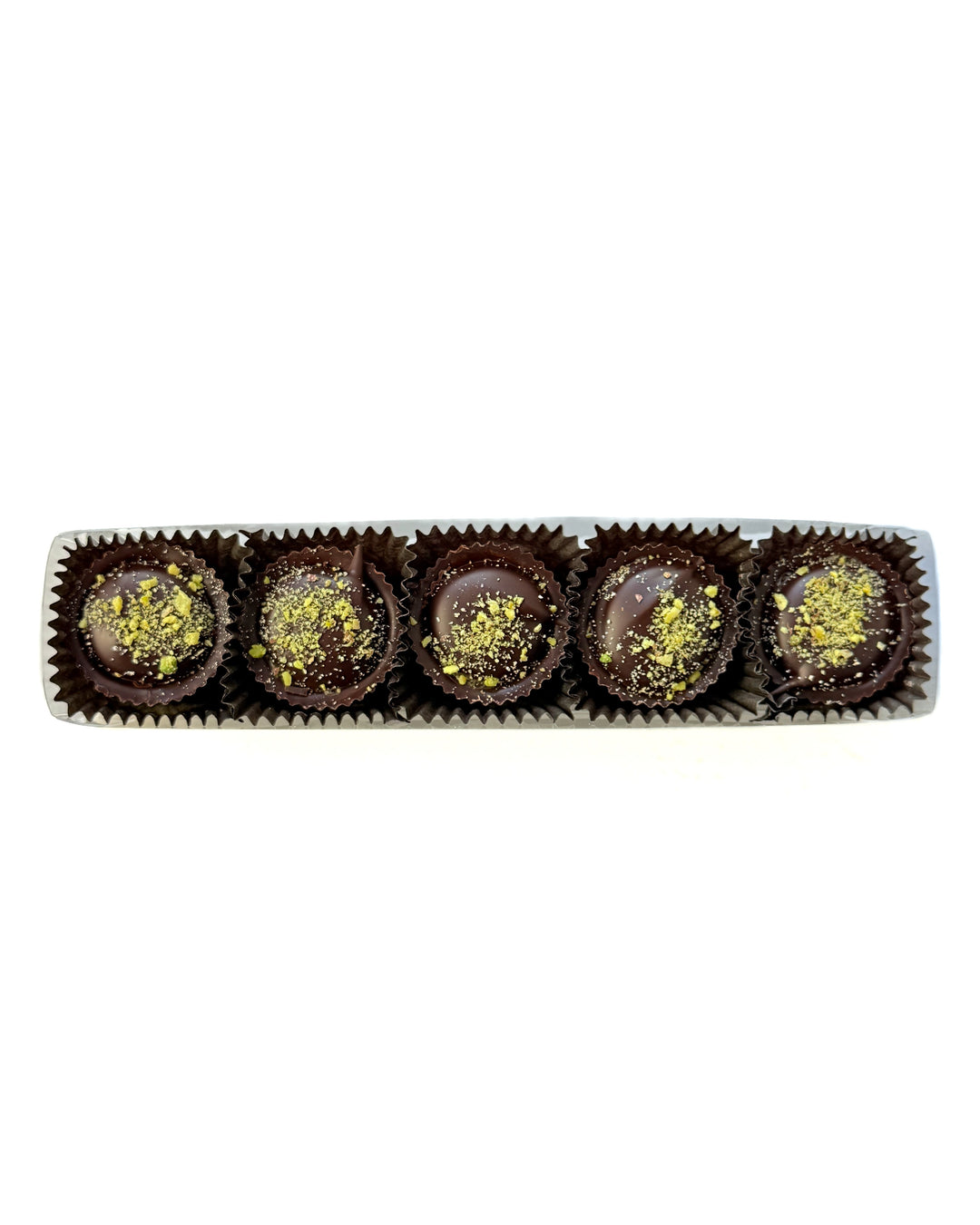 Five Dark Chocolate Pistachio Crunch Cups by Ragged Coast Chocolates sit in brown paper cups, topped with pistachio-tahini cream, arranged in a white box on a white background.
