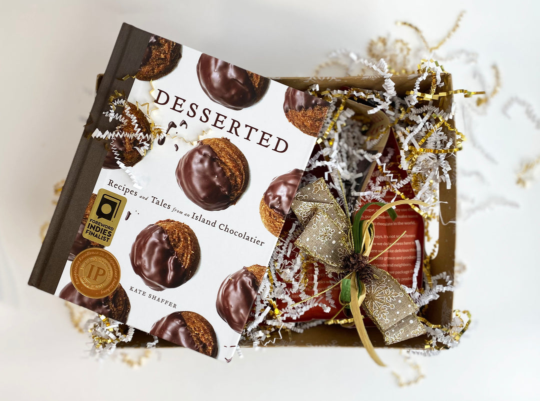 A hardcover cookbook titled "Baking Chocolate Gift Box w/Desserted" surrounded by festive decorations and a gift box on a flat surface.