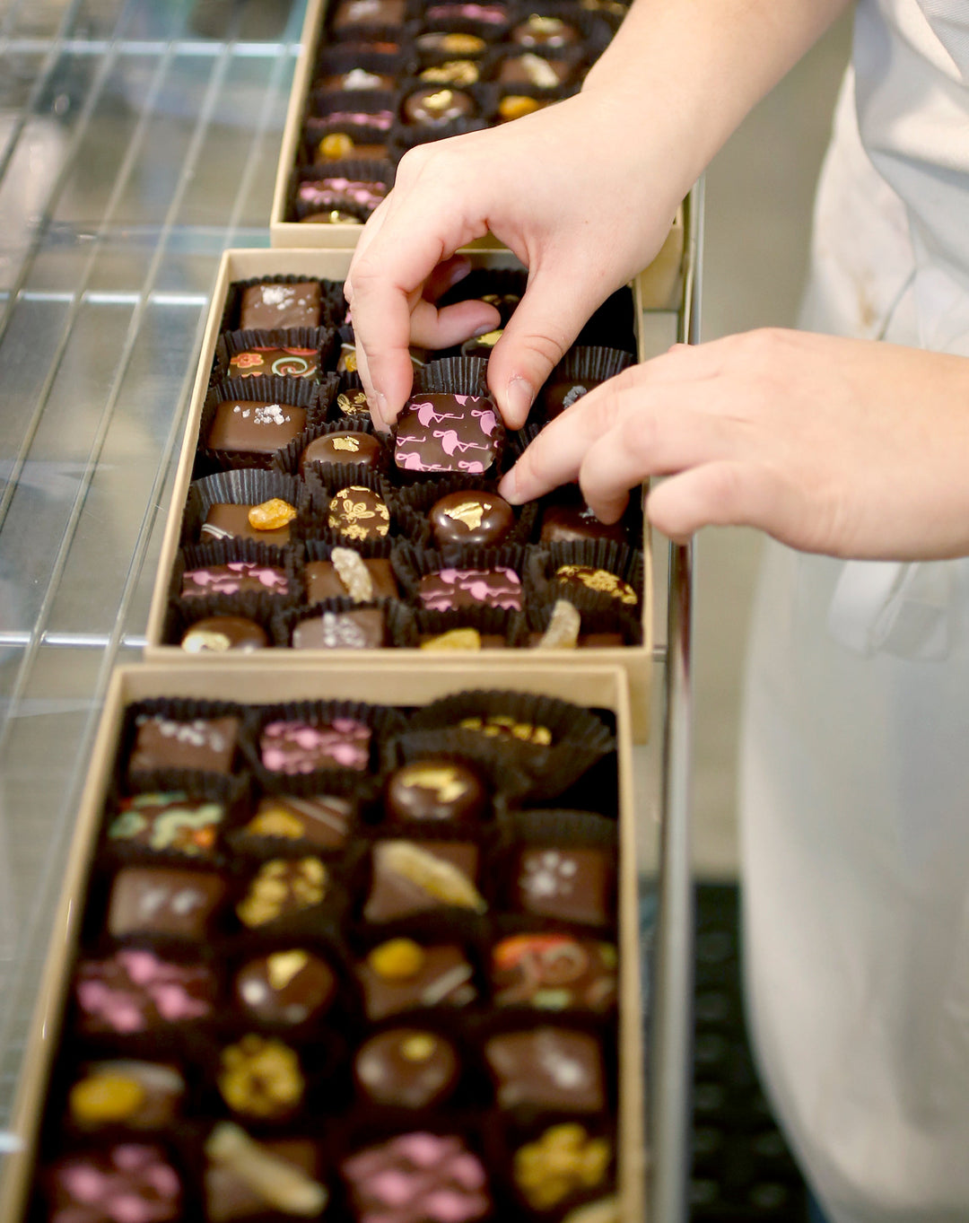 A person arranging assorted chocolates in a box.