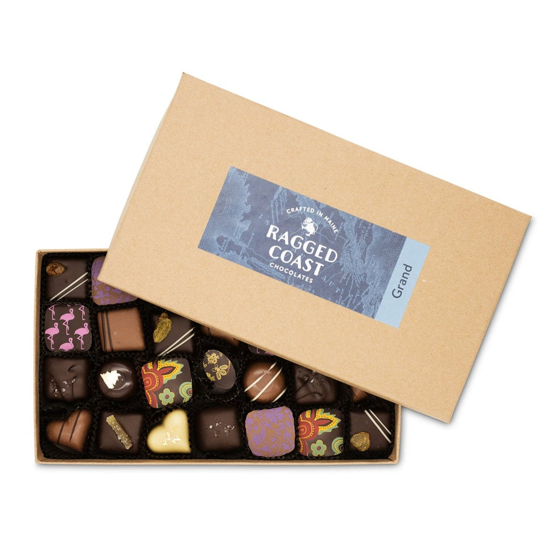 An open box of Ragged Coast Chocolates' Grand Assortment of Milk and Dark Chocolate Truffles, with a variety of decorative designs on them.