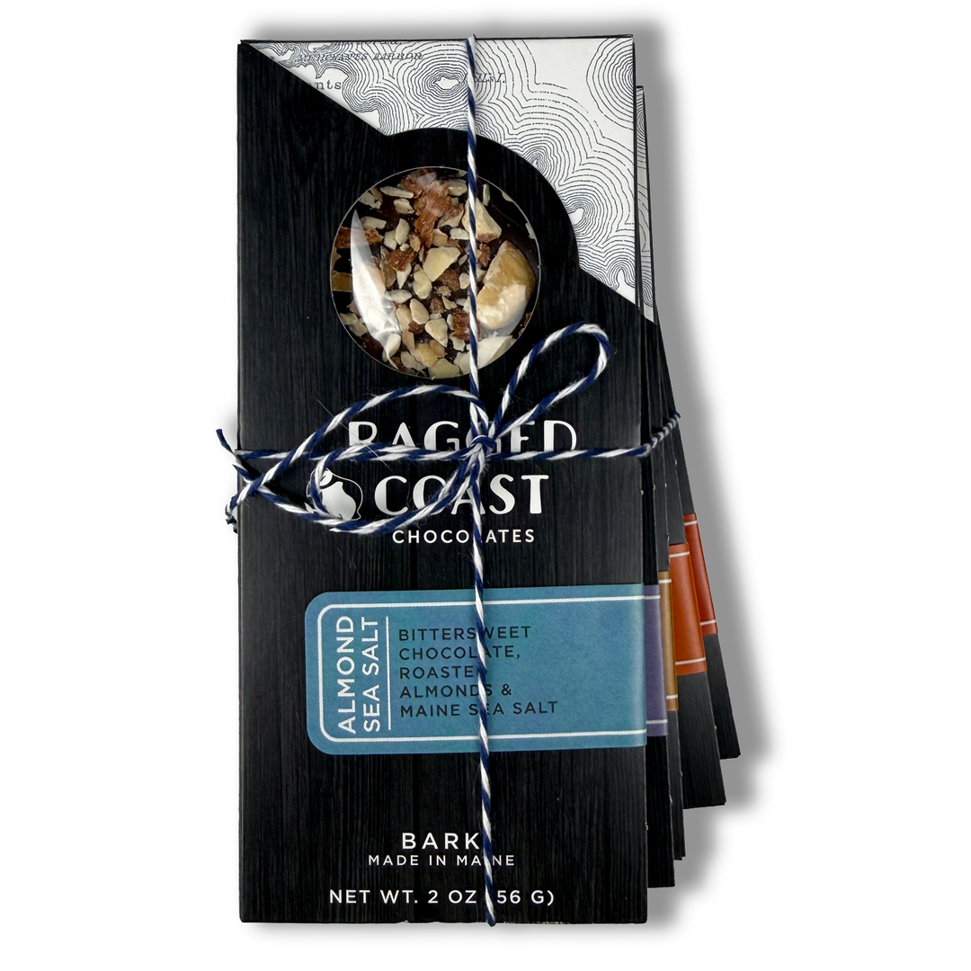 The Ragged Coast Chocolates Chocolate Bark Bundle features dark chocolate with roasted almonds, lemon, and Maine sea salt in a 2 oz vegan, gluten-free pack tied with blue and white string and a window showing the bark.