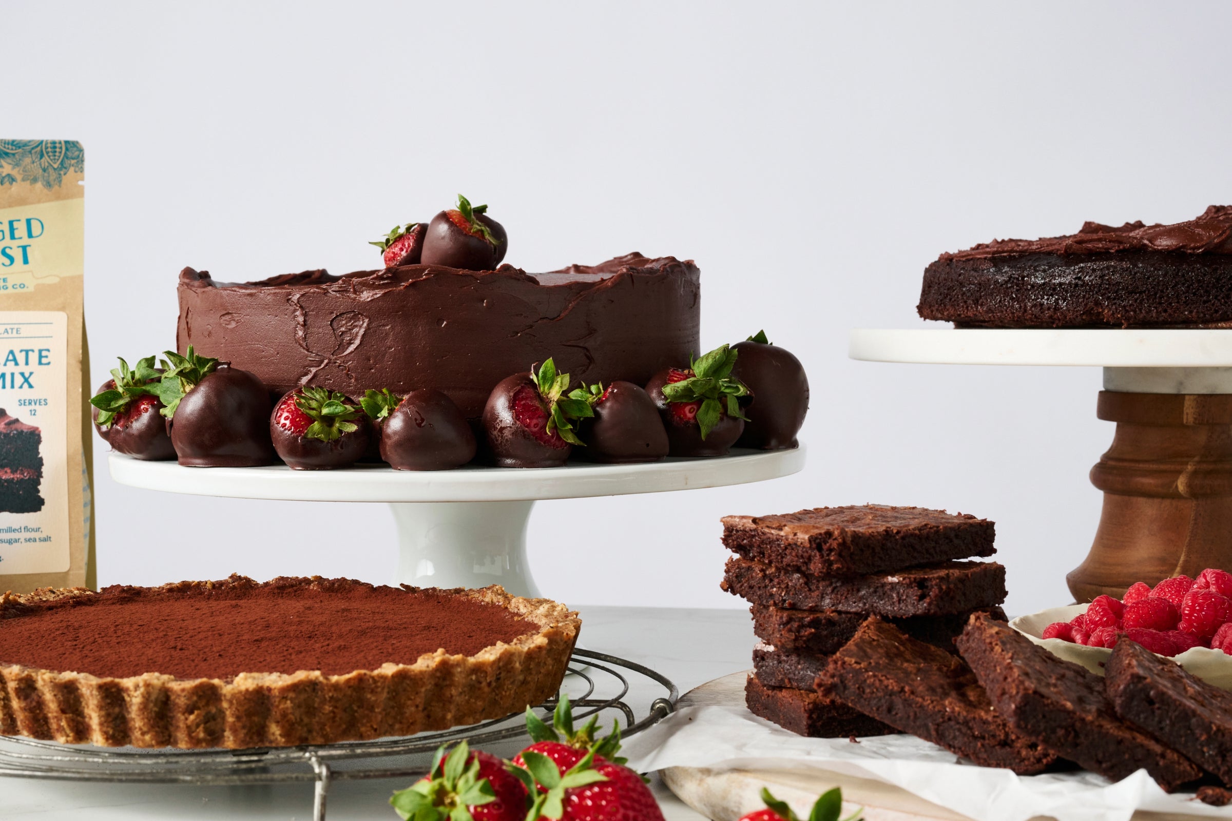 A selection of chocolate desserts, including a cake topped with strawberries, on display.