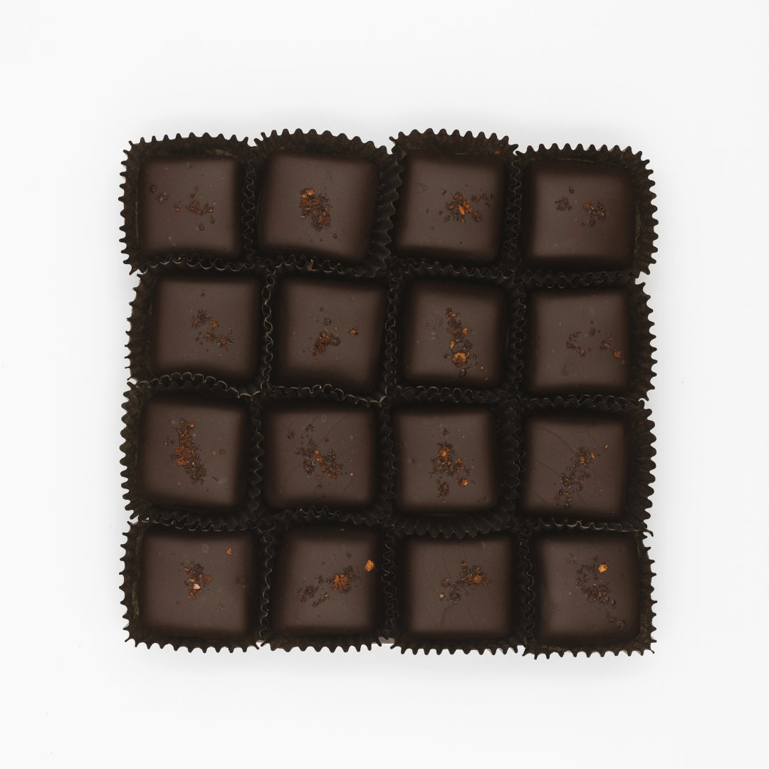 Box of dark chocolates with smoked sea salt on a white background