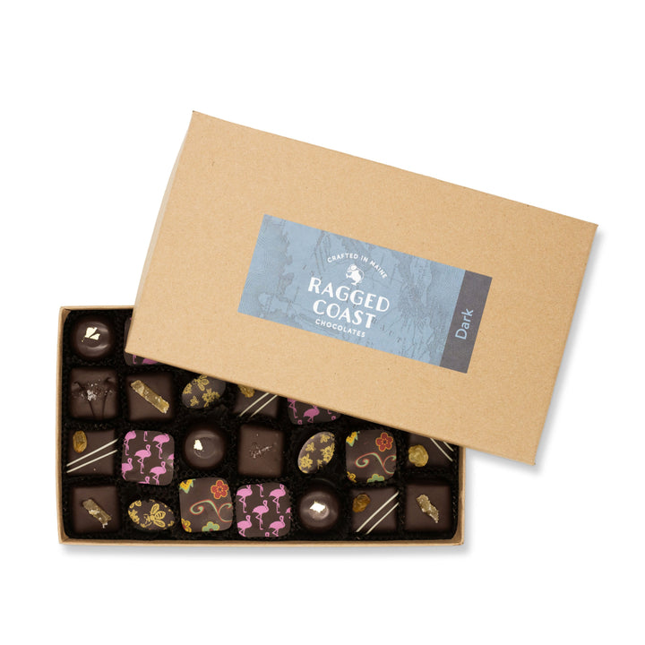 An open box of the Ragged Coast Chocolates Dark Chocolate Truffle Assortment, including dark chocolate truffles and dark chocolate sea salt caramels, with a ragged coast chocolates label on the recyclable paperboard lid.