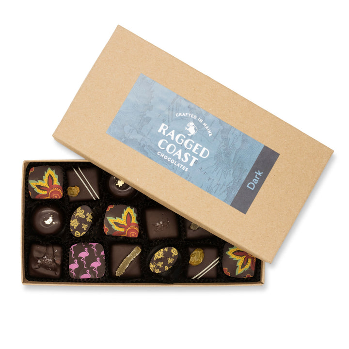 An open box of Ragged Coast Chocolates' Dark Chocolate Truffle Assortment, including dark chocolate sea salt caramels and dark chocolate truffles, with various decorative toppings.