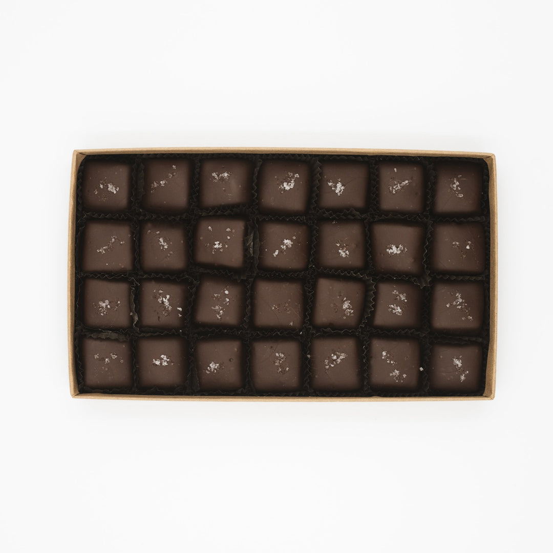 A box of Ragged Coast Chocolates' Flagship Sea Salt Caramels with a decorative topping on each piece.