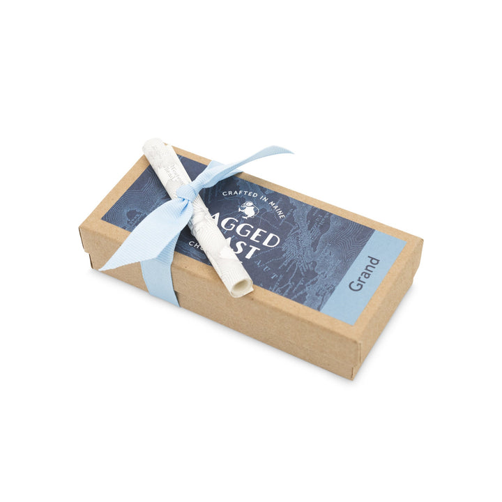 A small cardboard gift box with a blue ribbon and a label that reads "Ragged Coast Chocolates Grand Assortment of Milk and Dark Chocolate Truffles".