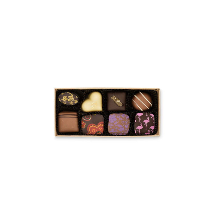A box of Ragged Coast Chocolates' Grand Assortment of Milk and Dark Chocolate Truffles, featuring diverse shapes and decorative designs on a white background.