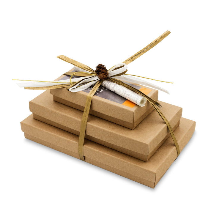 Stack of gift-wrapped books tied with a ribbon, decorated with a pine cone, and accompanied by Ragged Coast Chocolates Dark Chocolate Sea Salt Caramels.