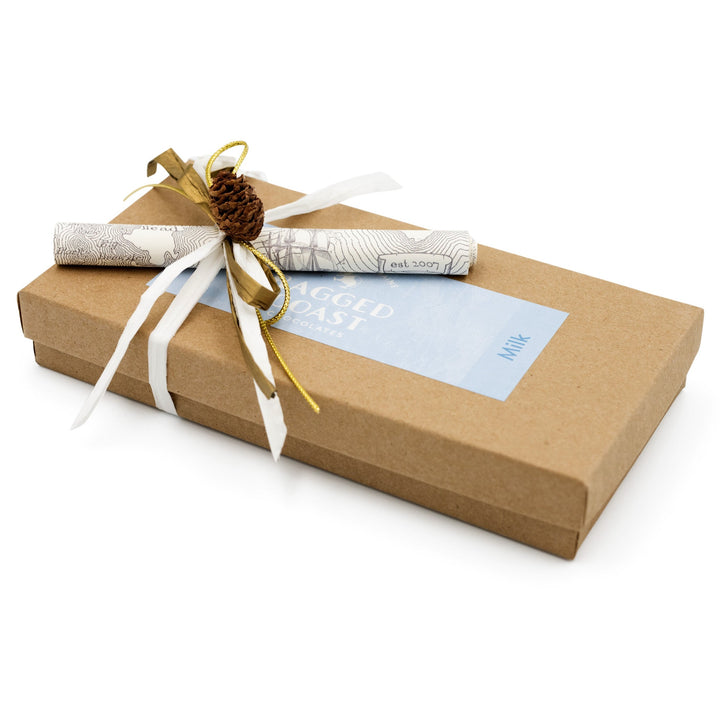 Gift box wrapped in brown recyclable paperboard with a decorative pine cone and string, accompanied by a card containing Ragged Coast Chocolates Milk Chocolate Truffle Assortment.