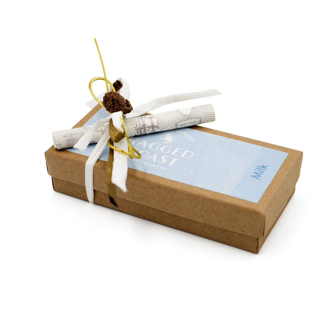 Elegantly presented Ragged Coast Chocolates Milk Chocolate Truffle Assortment gift box with a grosgrain ribbon and tag, isolated on a white background.