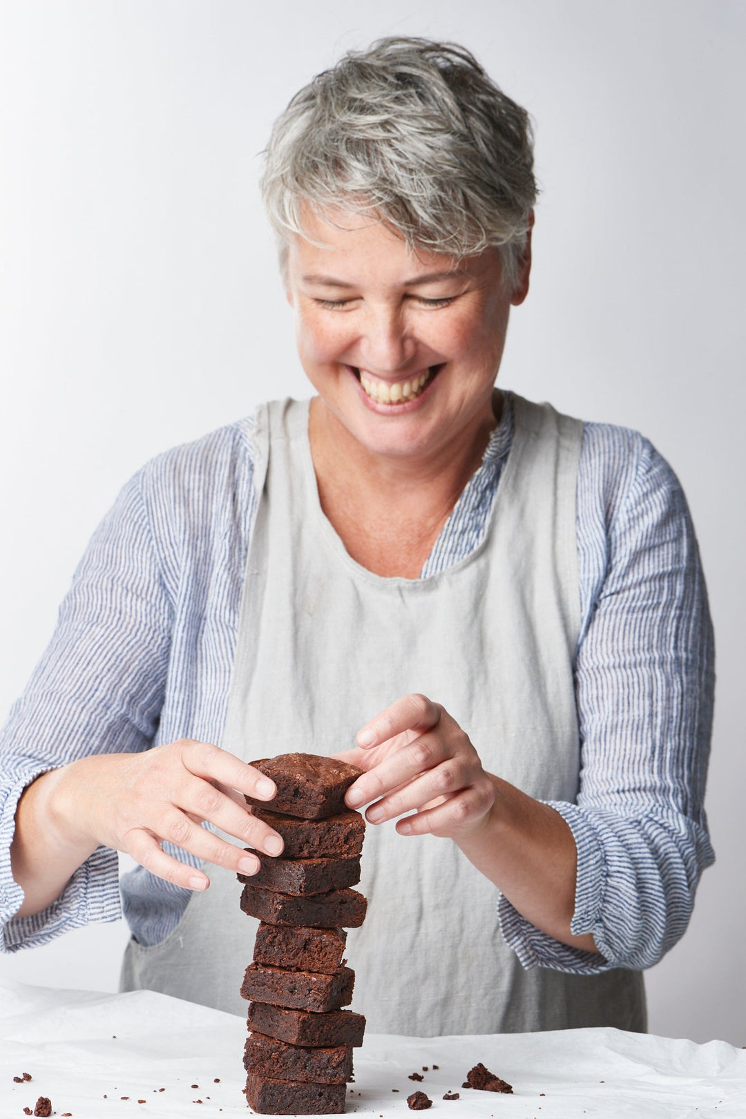 Woman stacking brownies with a joyful expression.