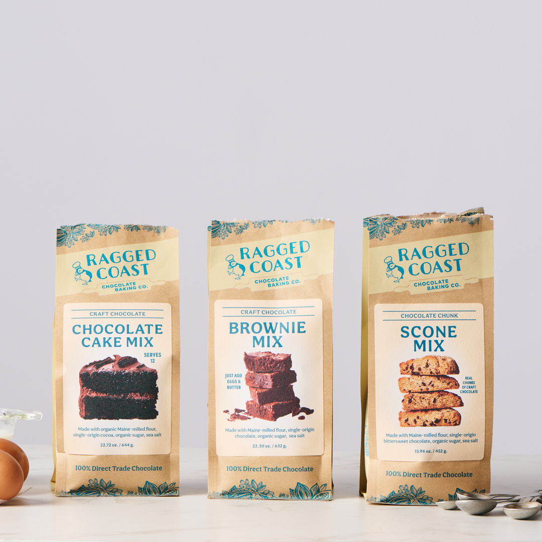 Three packages of Ragged Coast Chocolates Baking Mix Gift Box, including chocolate cake mix, brownie mix, and chocolate chip scone mix, displayed against a light background.