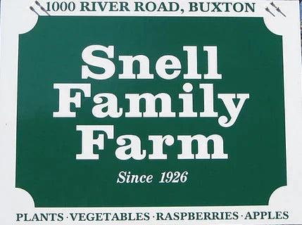 A sign for snell family farm, advertising plants, vegetables, raspberries, and apples, established in 1926.