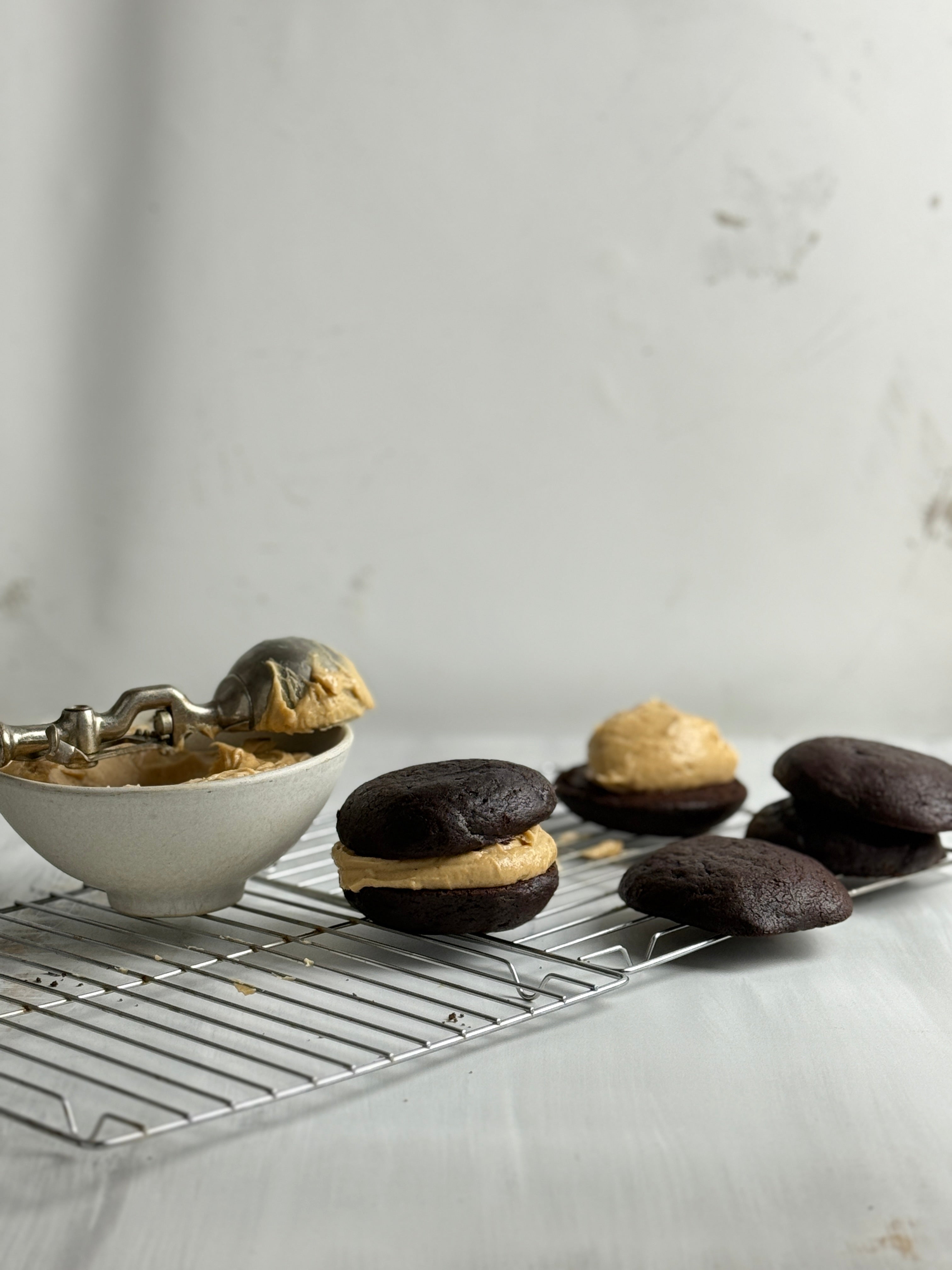 whoopie pies with peanut butter filling on a cooling rack against a light gray background