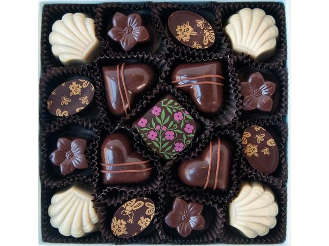 Assorted chocolates in various shapes, including hearts and shells, with decorative patterns such as Bon Bon Bouquet 17-piece Box, presented in a black box from Ragged Coast Chocolates.