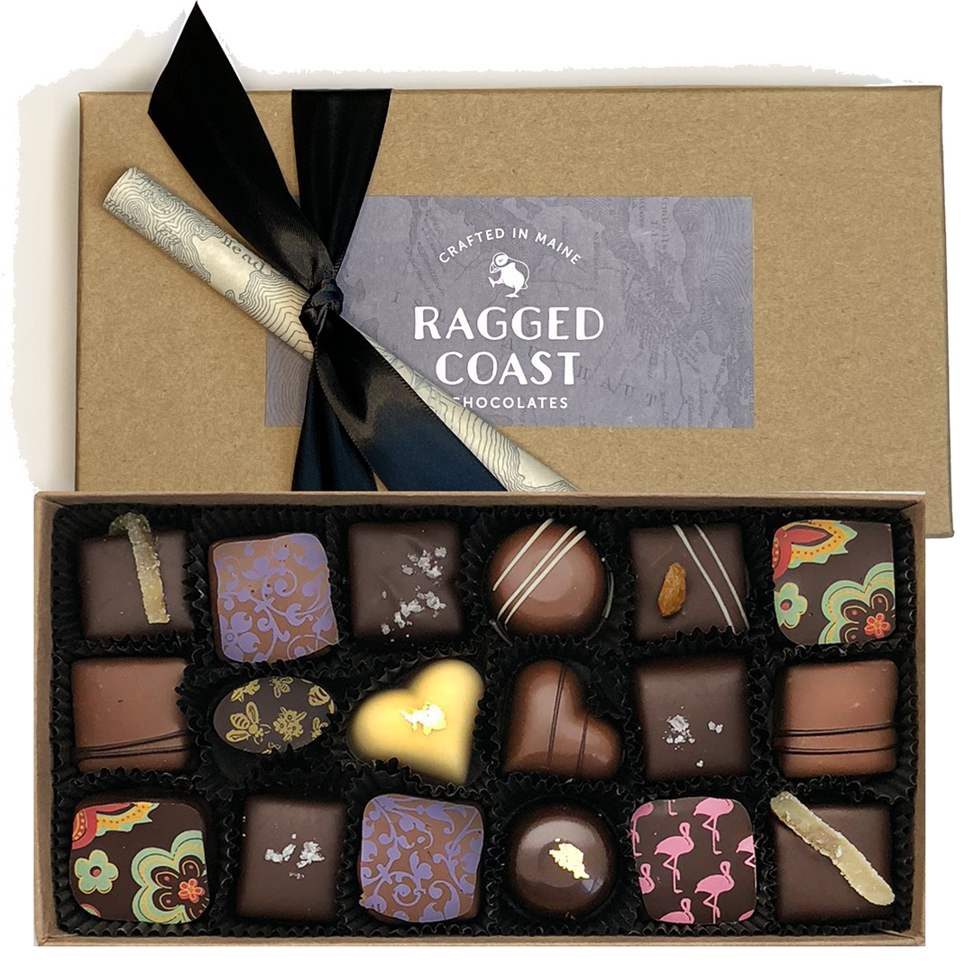 A box of assorted artisan chocolates from the Ragged Coast Chocolates Grand Assortment collection with a custom ribbon and a brand label on the lid.