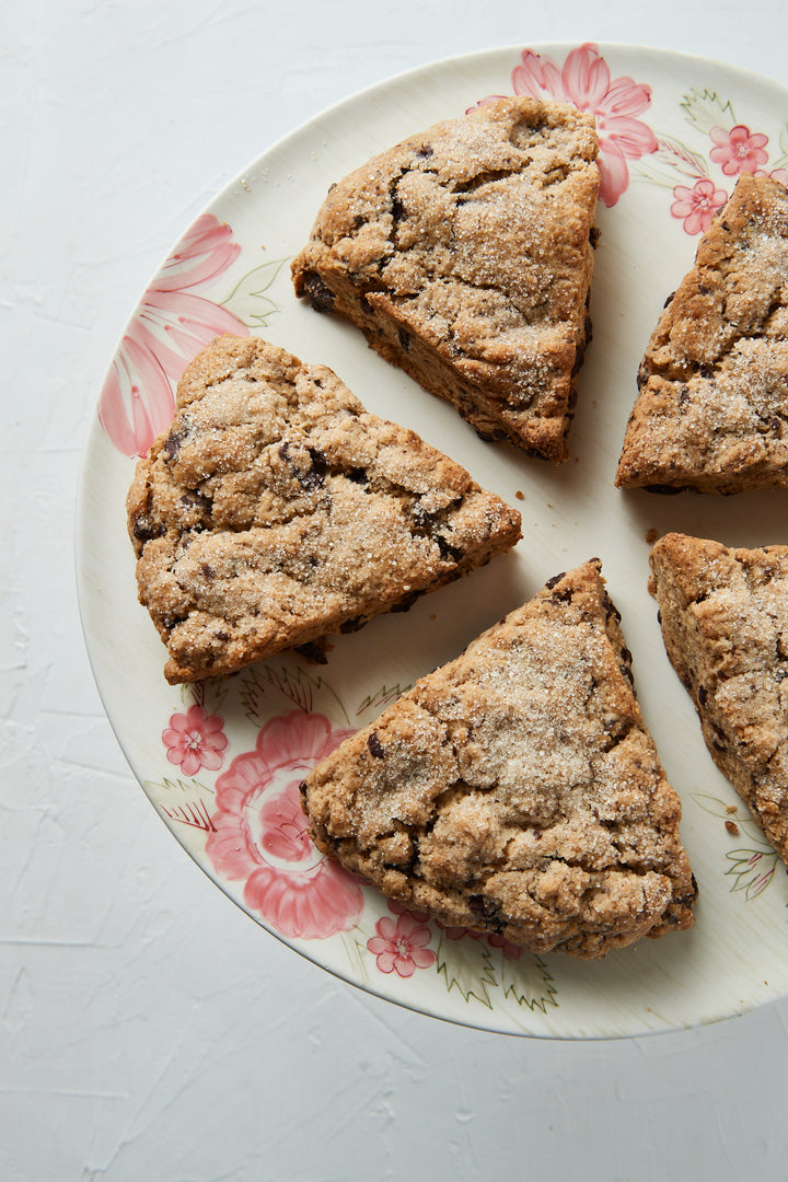 Four triangular scones made from Ragged Coast Chocolates Baking Mix Gift Box on a floral plate.