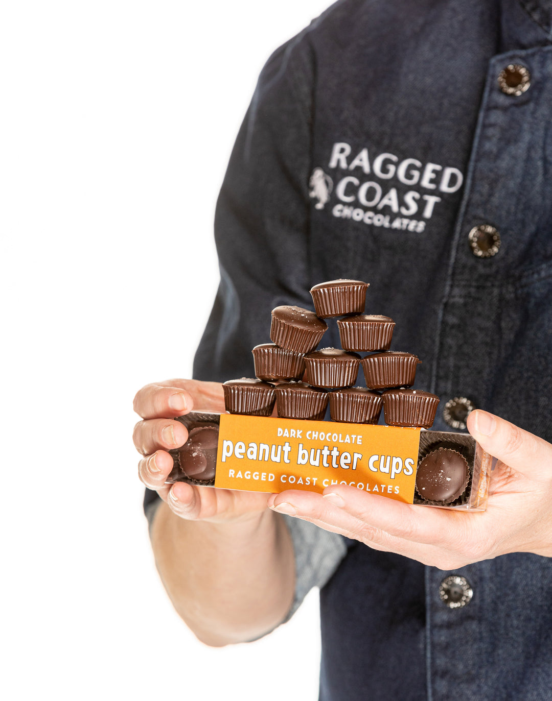 Person holding a stack of organic Ragged Coast Chocolates Dark Chocolate Peanut Butter Cups.
