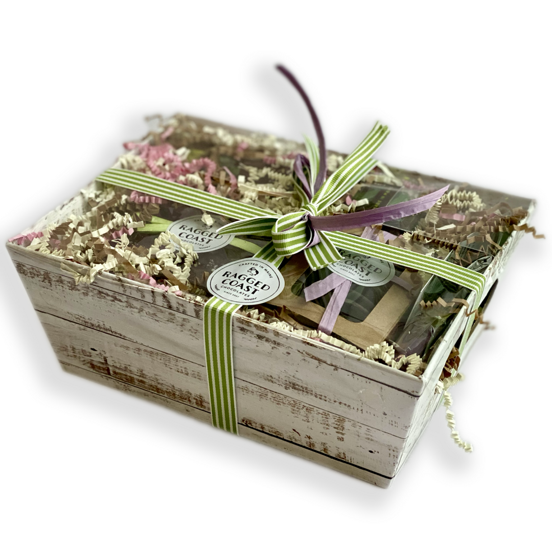 A rustic Ragged Coast Chocolates Passover gift box adorned with a green and white striped ribbon and filled with Chocolate-Covered Toffee Matzos.