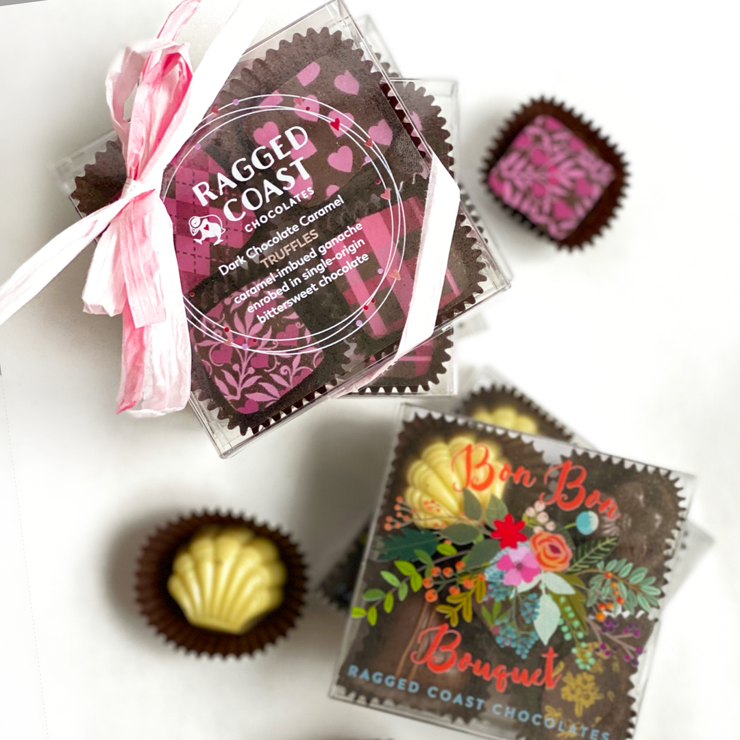 Assorted Pocket Chocolates: Mini Bon Bon Bouquet and Dark Chocolate Caramel Truffles by Ragged Coast Chocolates, with decorative packaging featuring floral designs, displayed on a light surface in limited-edition gift boxes.